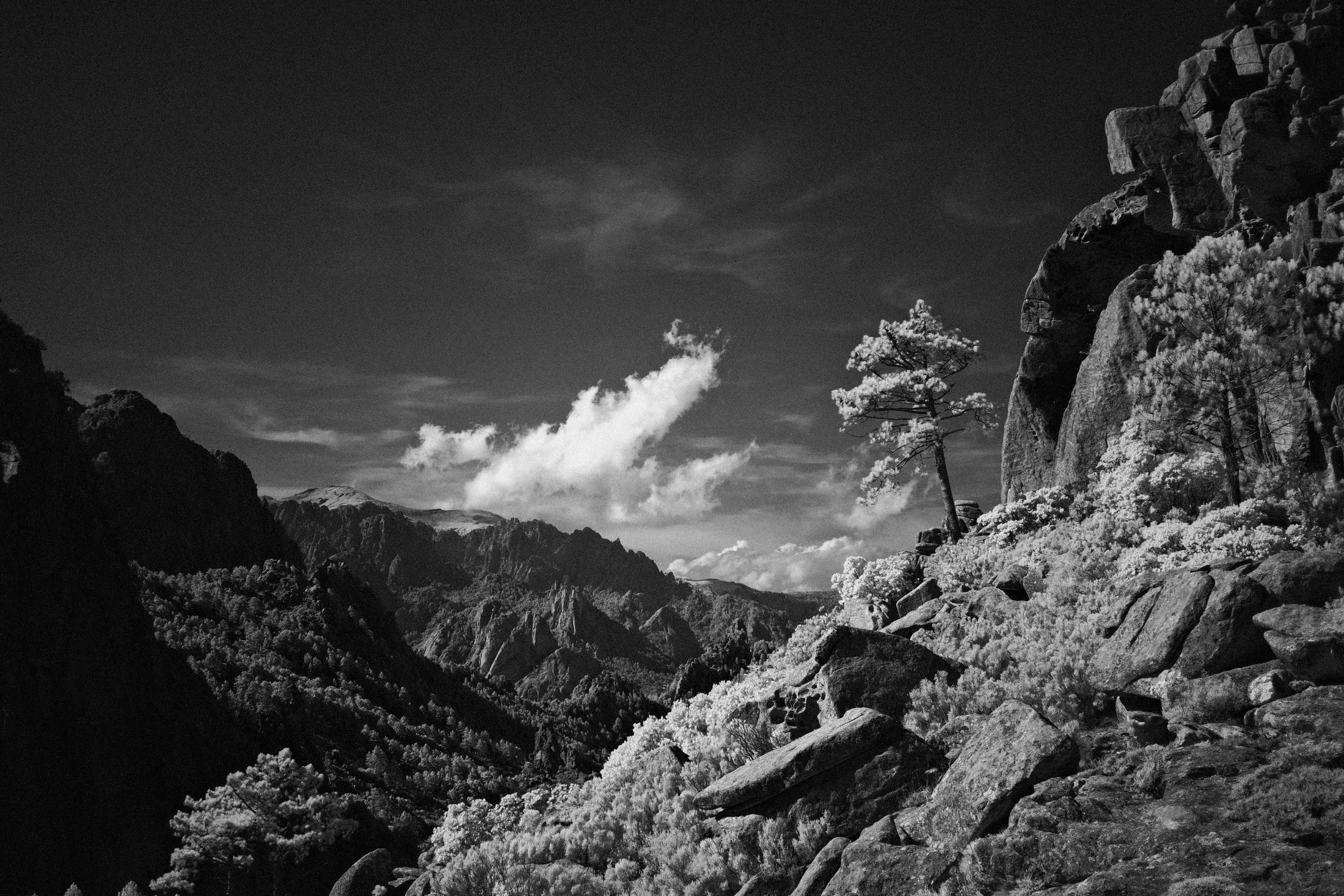 Black and white rocky mountain slopes rising beneath streaked clouds.