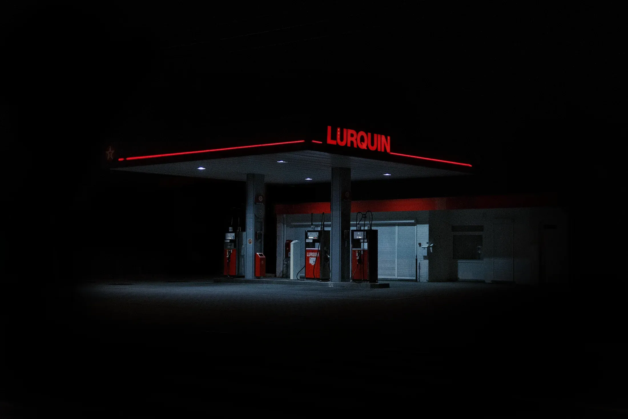 Isolated petrol station glowing red and white in surrounding darkness.