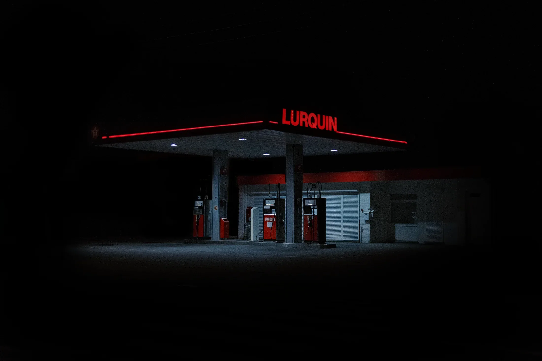Isolated petrol station glowing red and white in surrounding darkness.