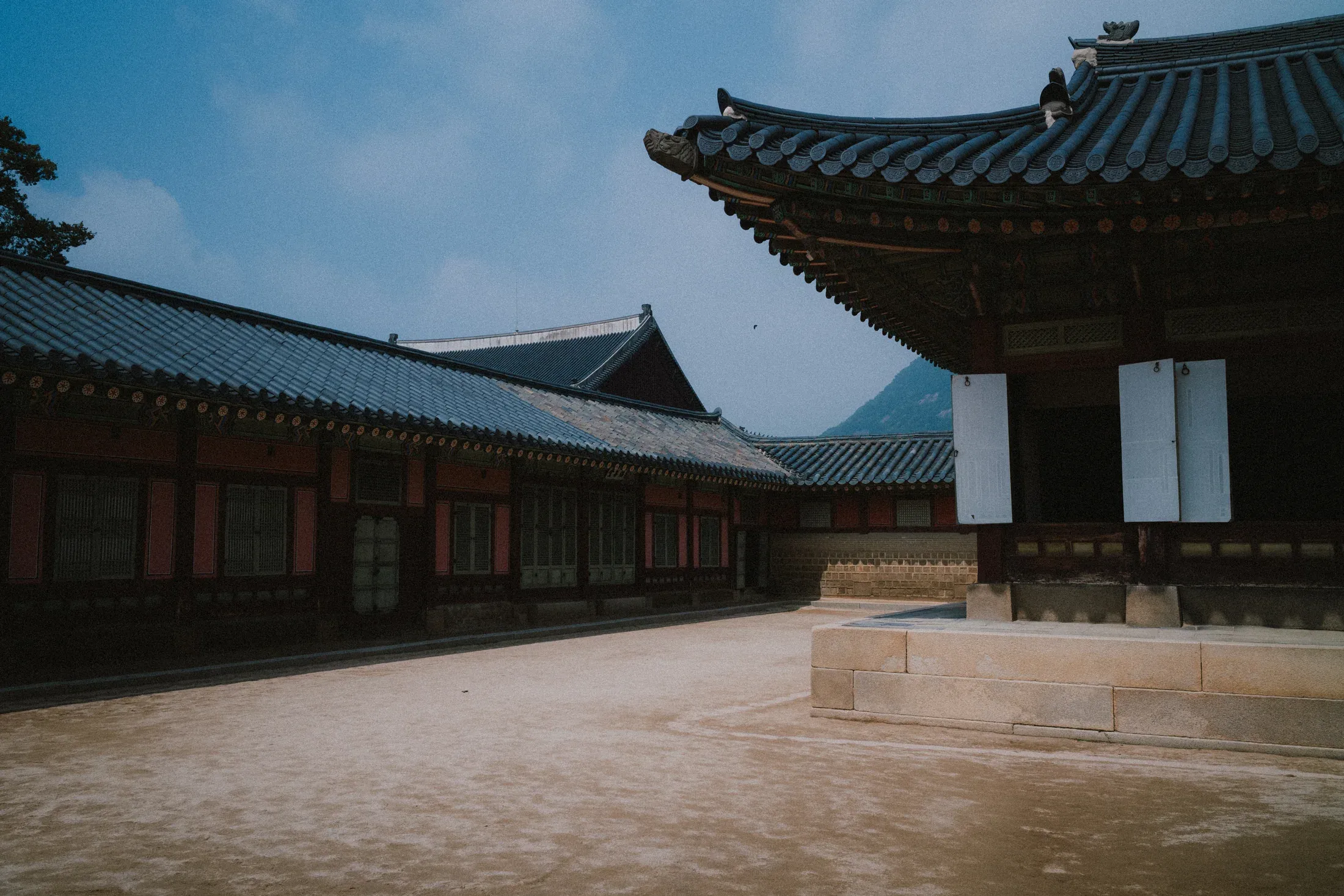 Empty palace courtyard bordered by colorful traditional buildings under a blue roofline.