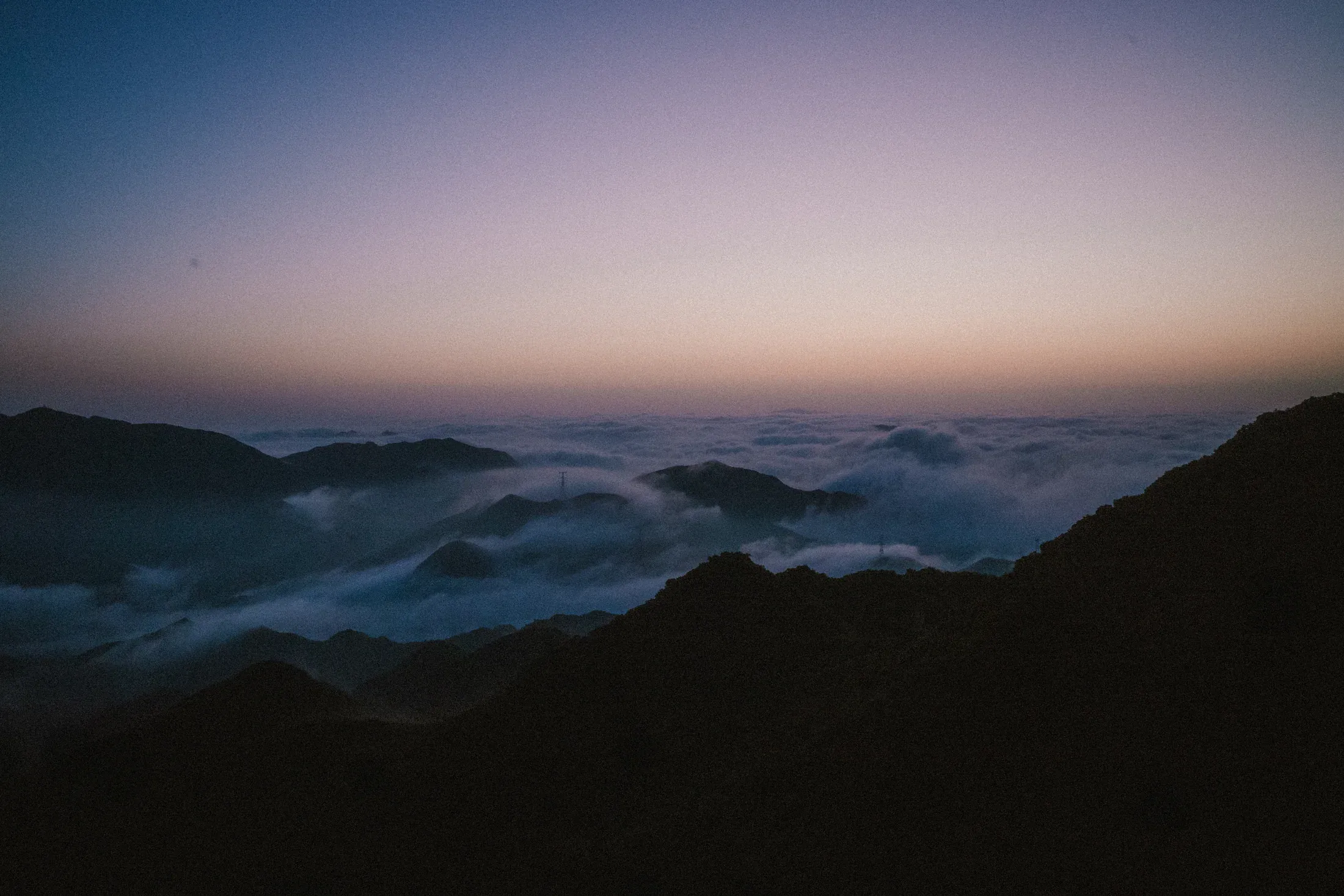 Blue dusk over layered mountain ridges and a sea of cloud.