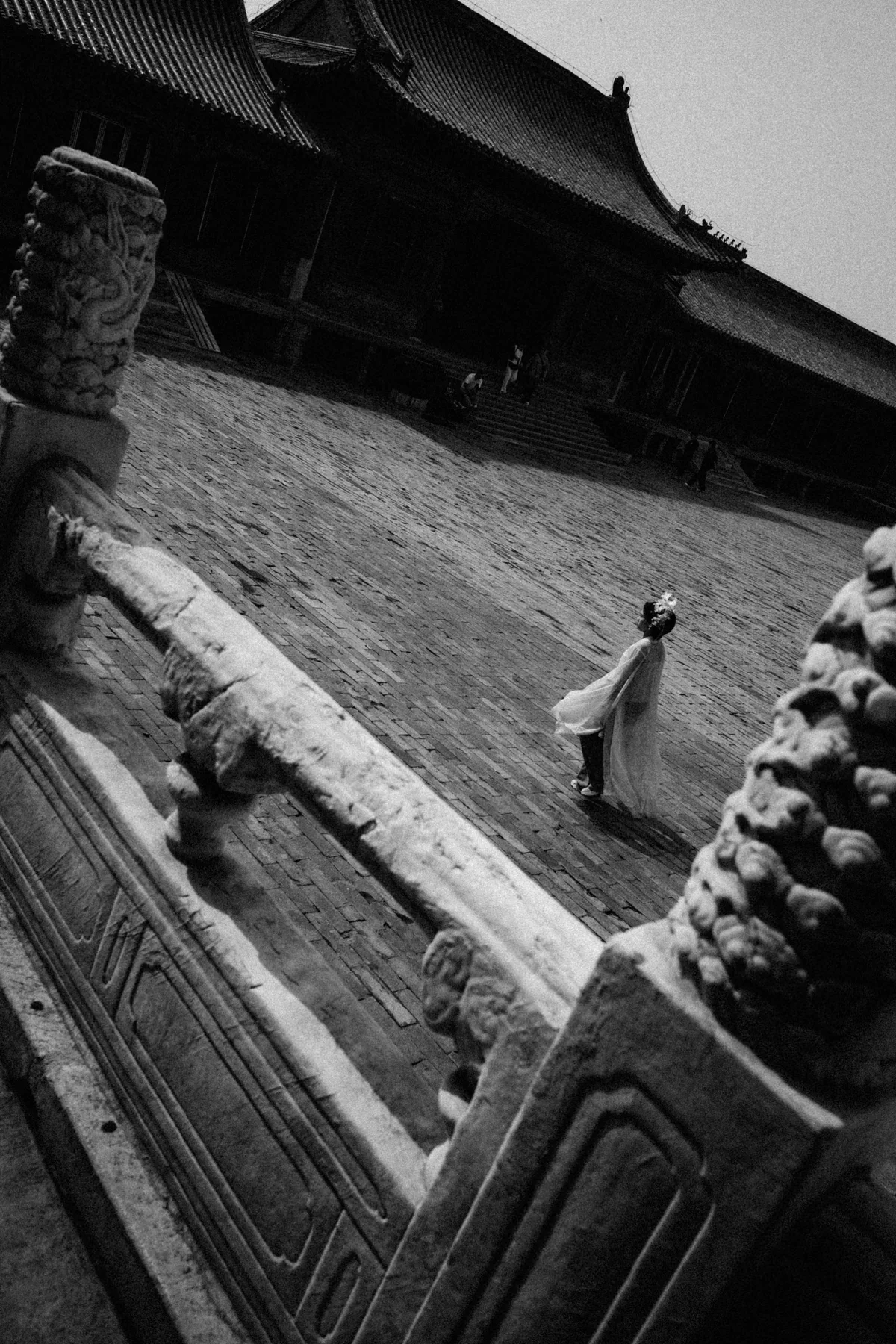 Steep black and white view across palace stonework with visitors below.